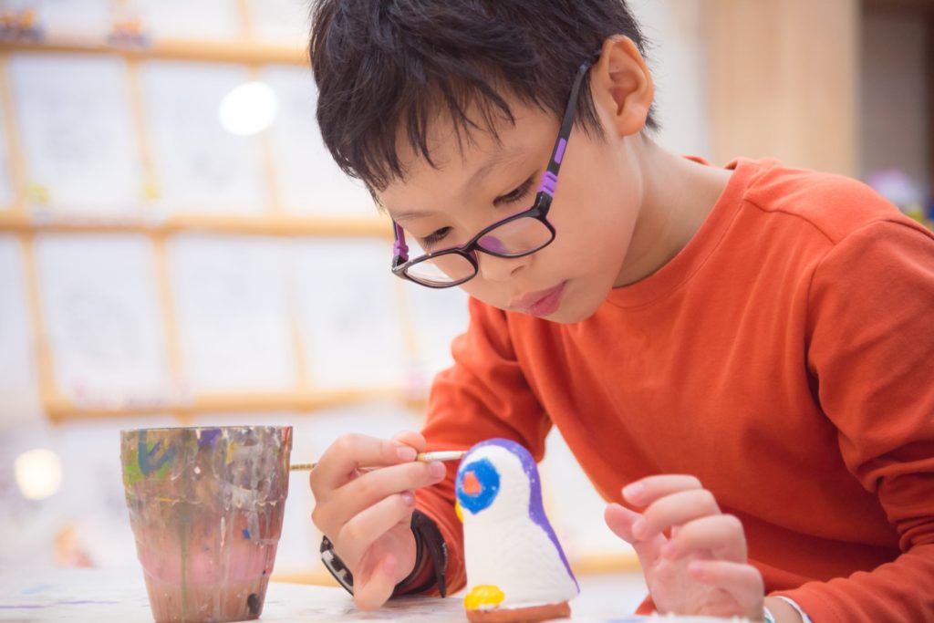 boy painting pottery figure